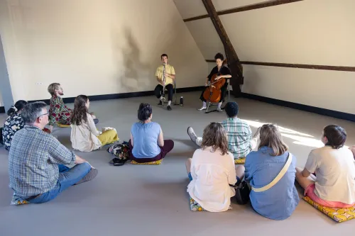 Kleinschalige performance met publiek zittend op kussens op de zolderverdieping.